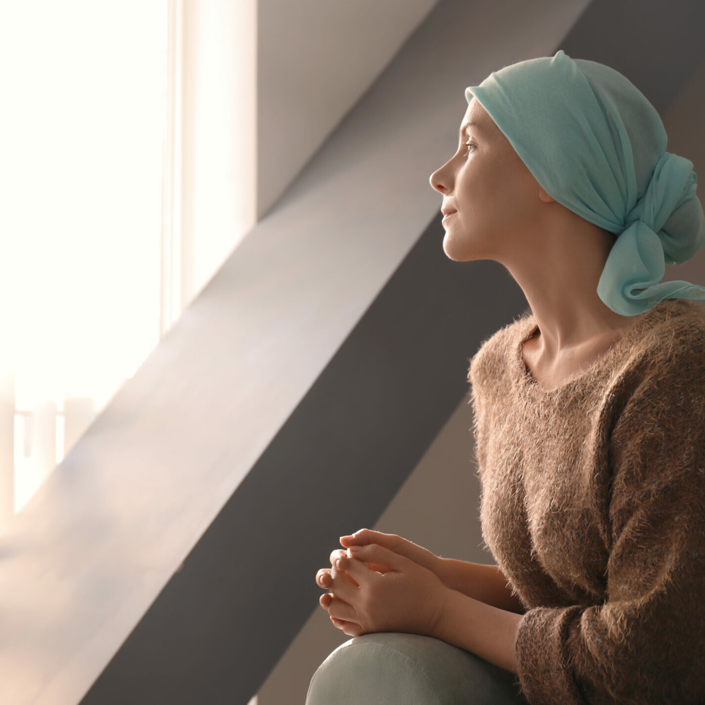 Young woman with cancer in headscarf indoors