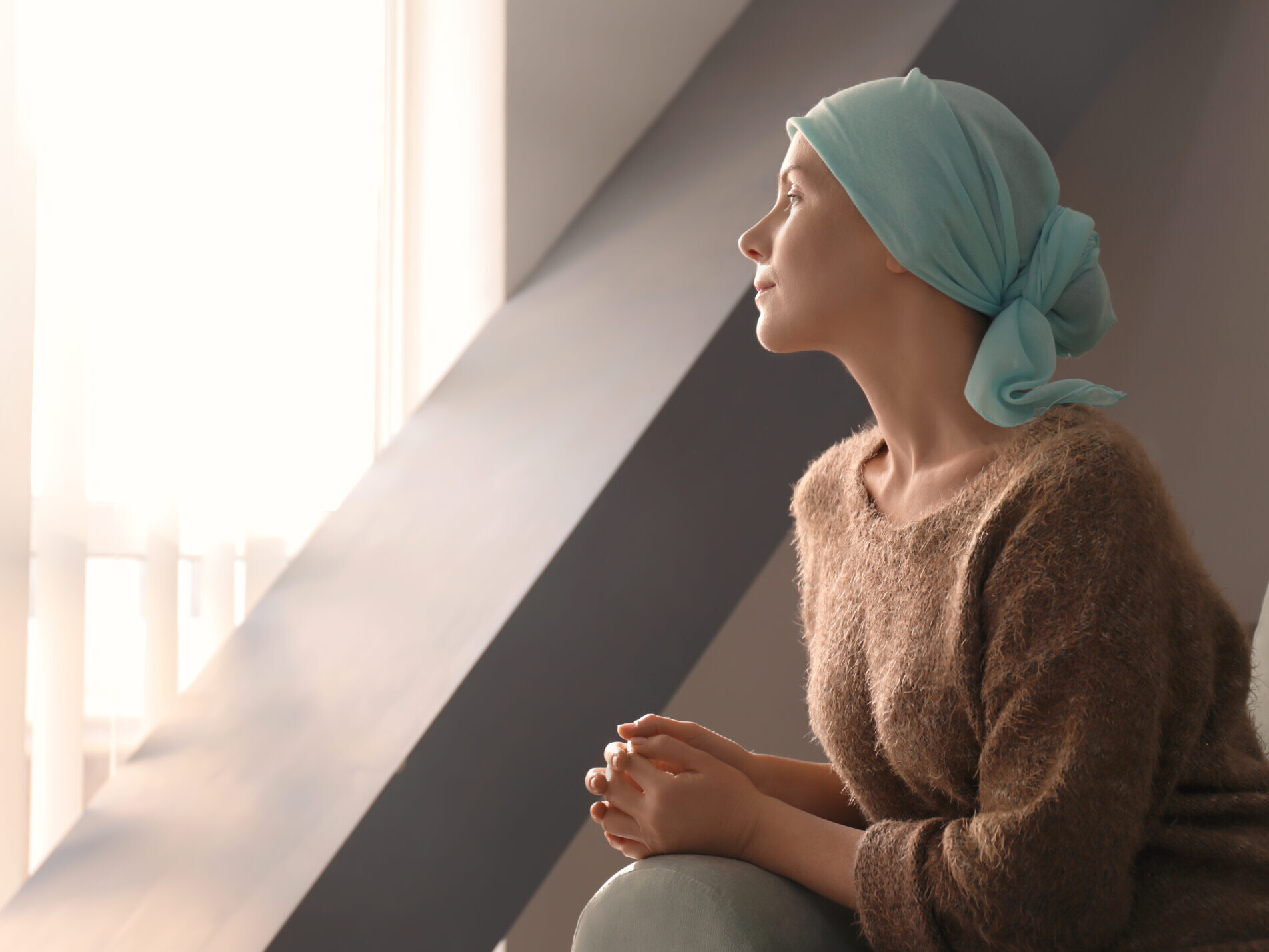 Young woman with cancer in headscarf indoors